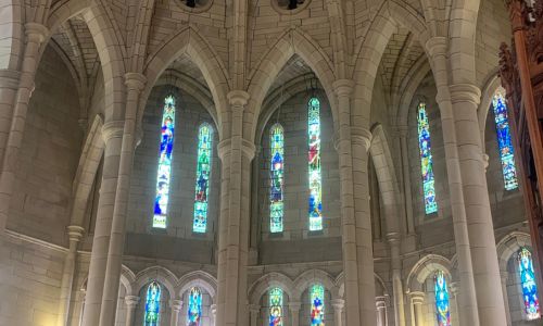 Interior of a cathedral with stained glass windows and arches.