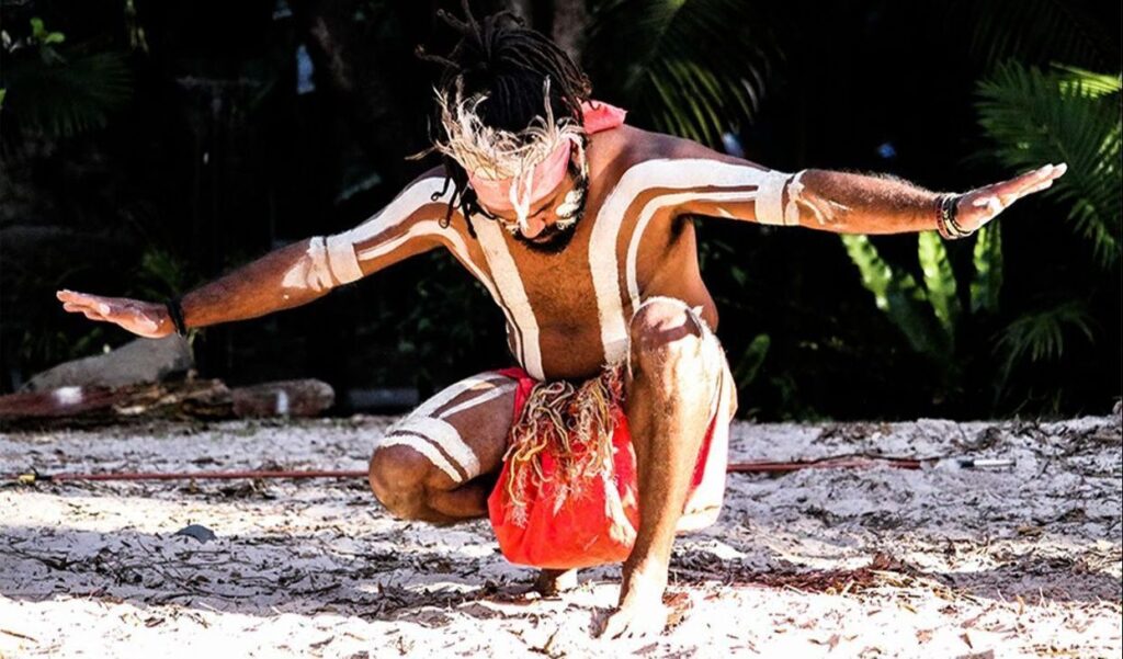 Person performing traditional dance with body paint outdoors.