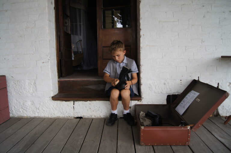A boy sitting cleaning boots at National Trust Wolston Farmhouse